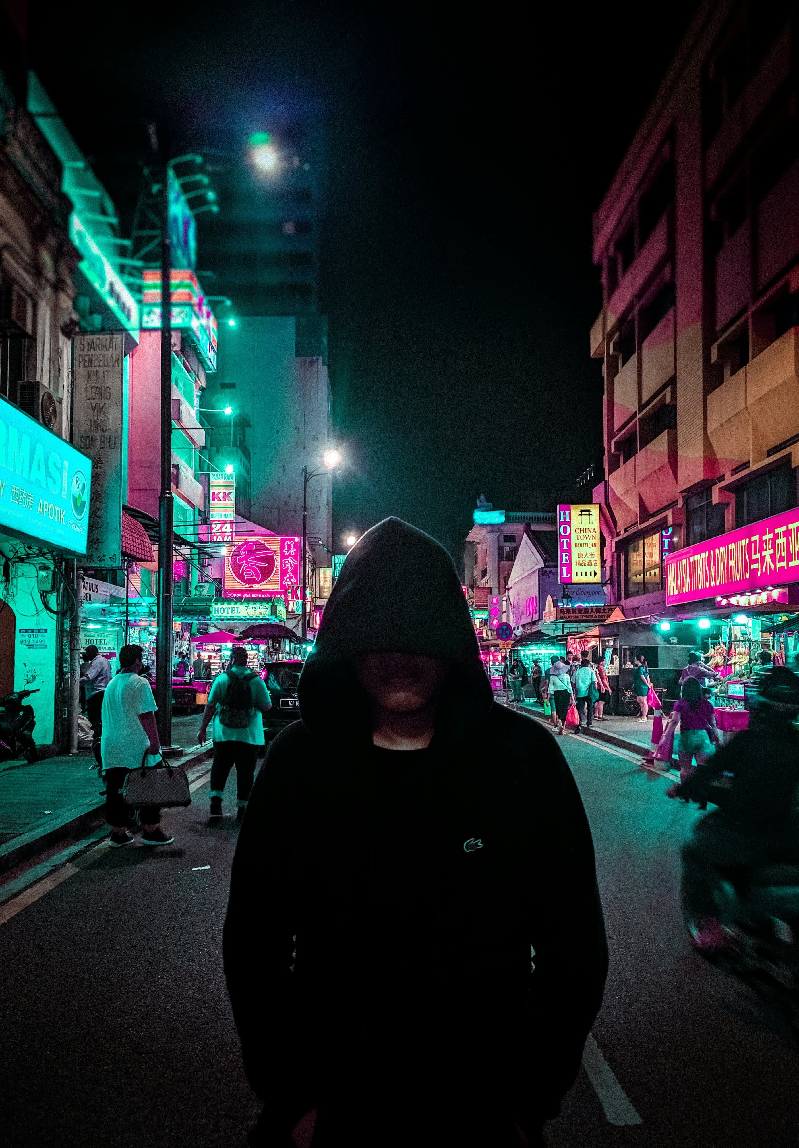 man in black hoodie walking on street during night time