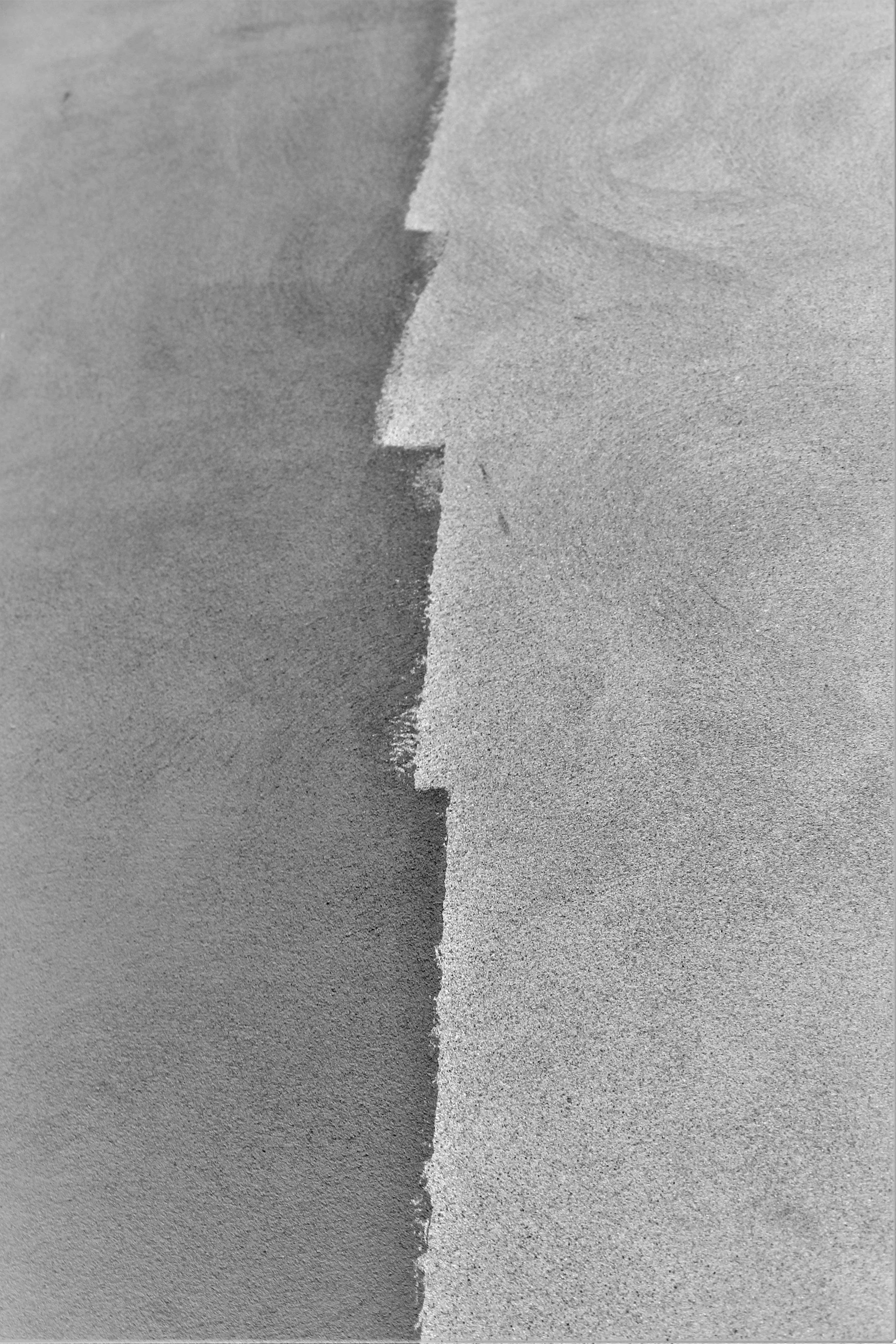 a black and white photo of a wave in the sand