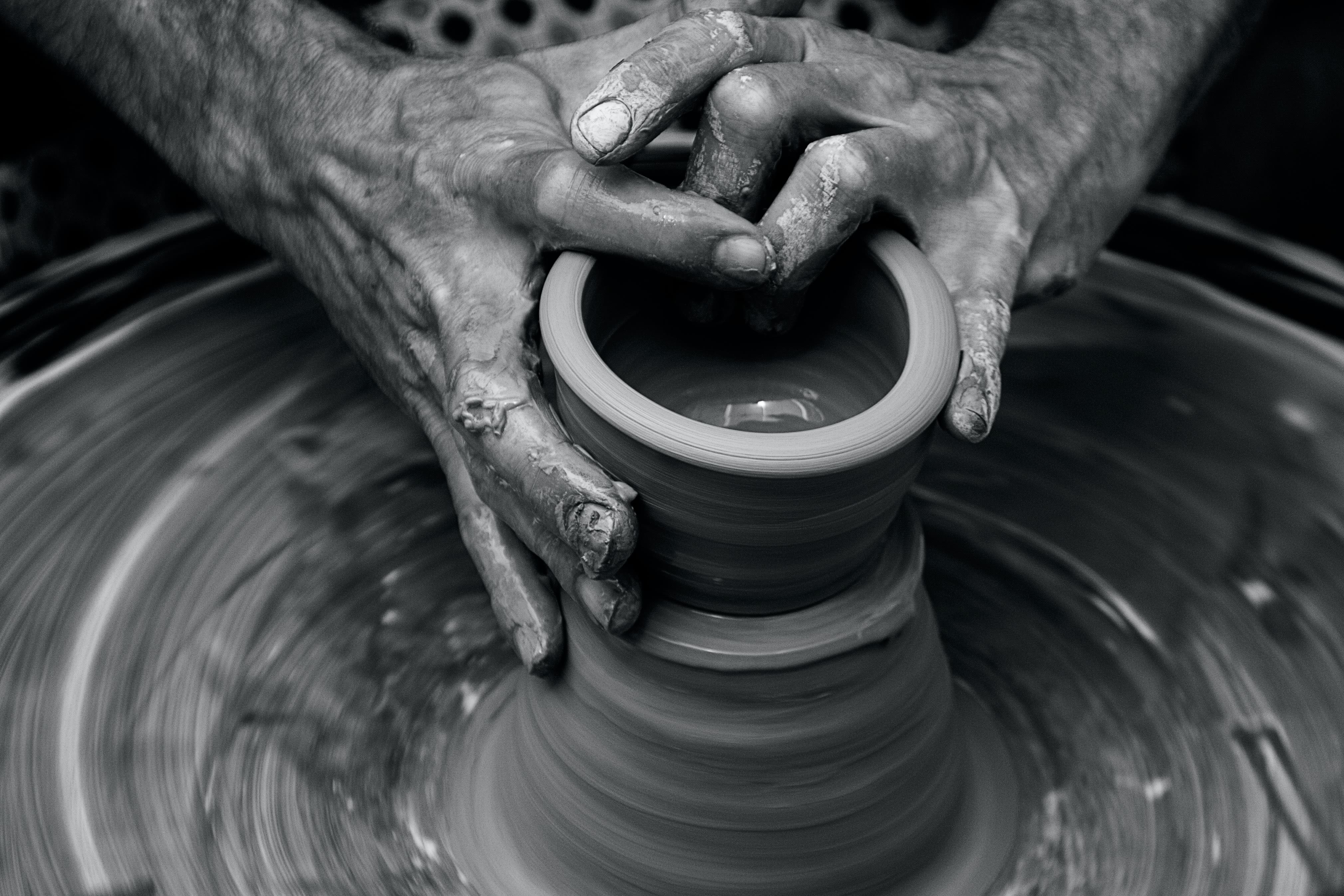 Messy hands sculpting on a pottery wheel in motion