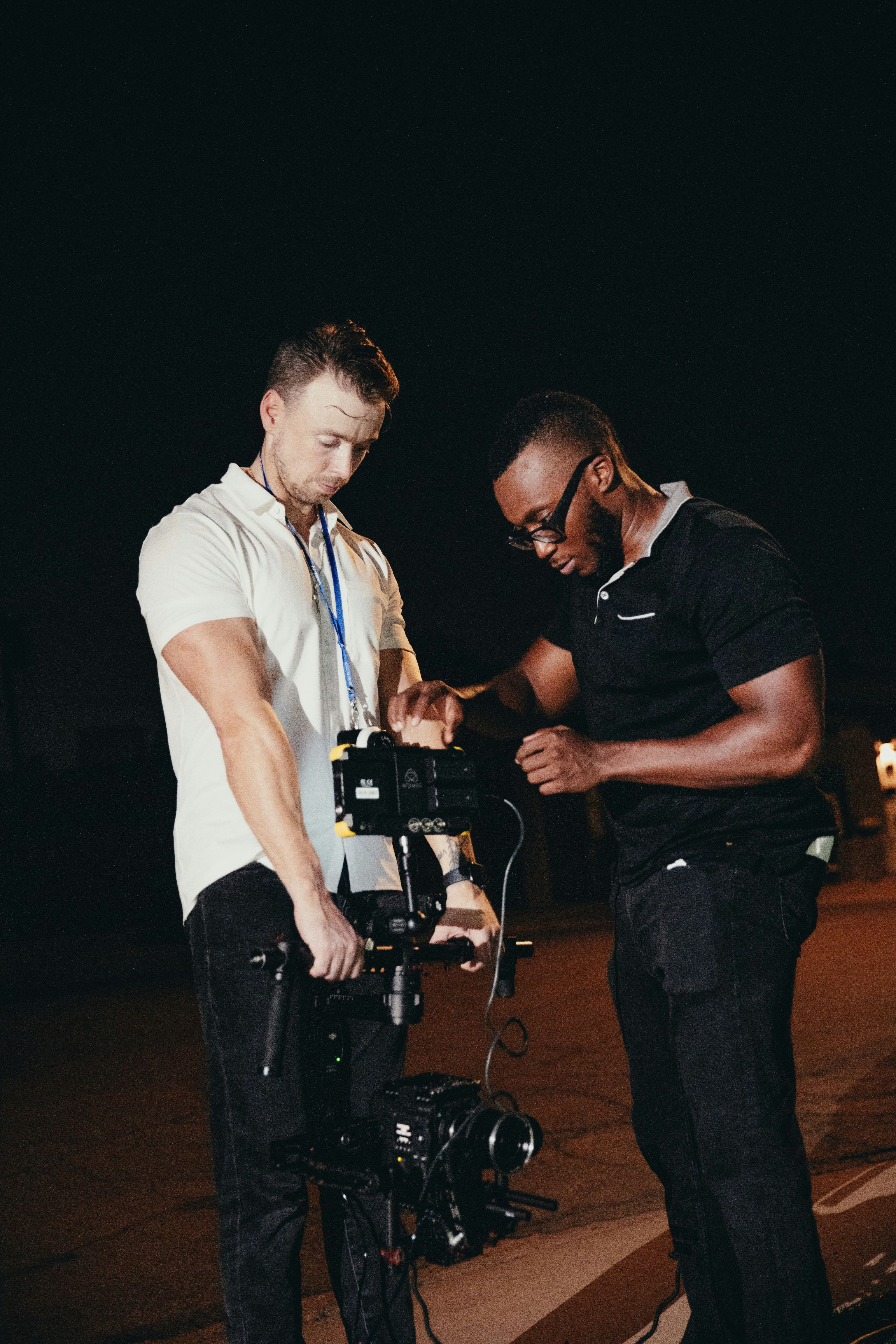 man in black crew neck t-shirt standing beside man in white polo shirt